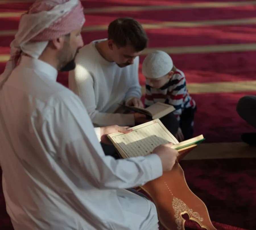 A male Quran teacher reading from the mushaf